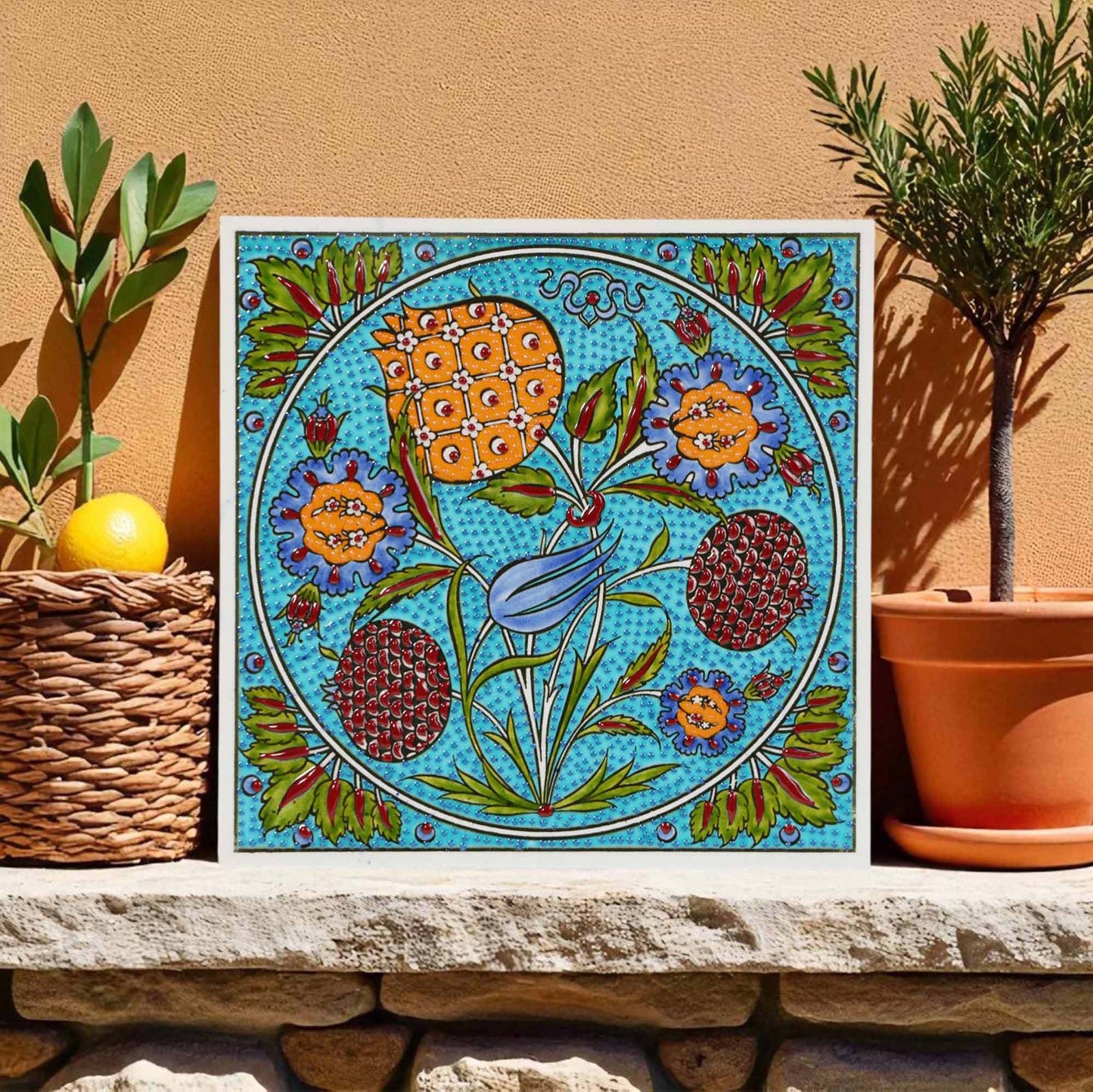 Decorative ceramic tile with floral design on a stone ledge with plants in the background