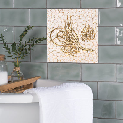 Decorative ceramic tile with Arabic calligraphy on a tiled wall.