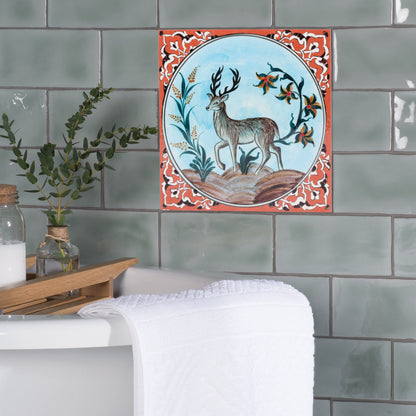 Decorative ceramic tile with deer design on a tiled wall.