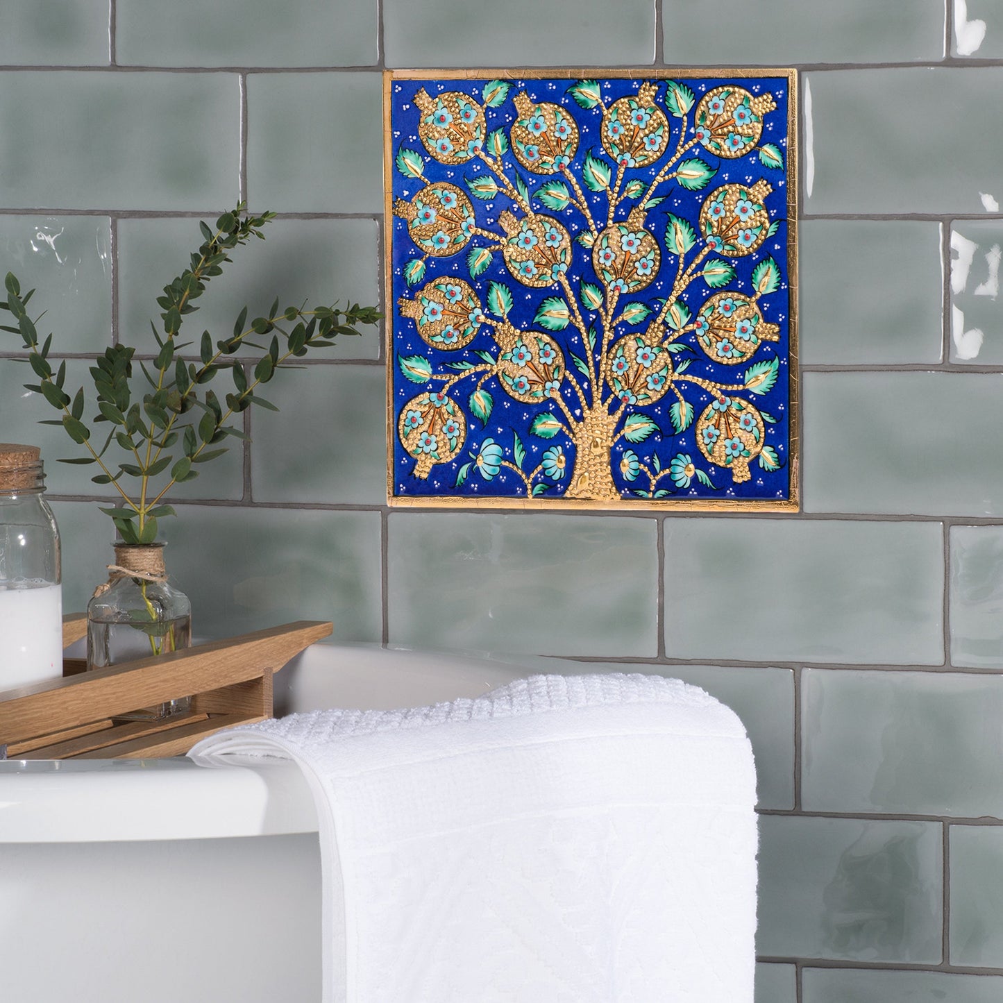 Decorative ceramic tile of a tree with blue background on tiled wall.