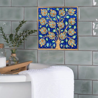 Decorative ceramic tile of a tree with blue background on tiled wall.