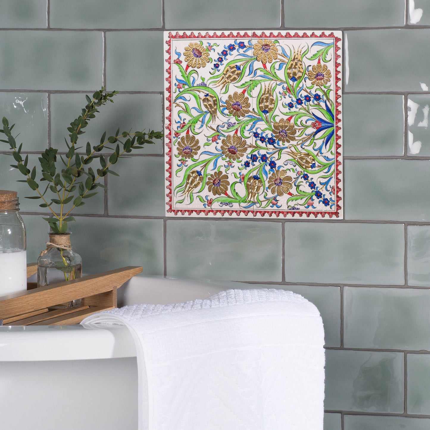 Decorative ceramic tile with floral pattern on green tiled wall.