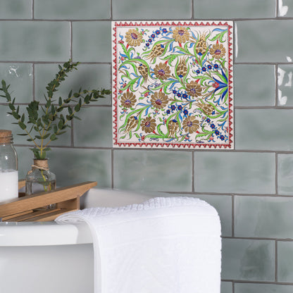 Decorative ceramic tile with floral pattern on green tiled wall.