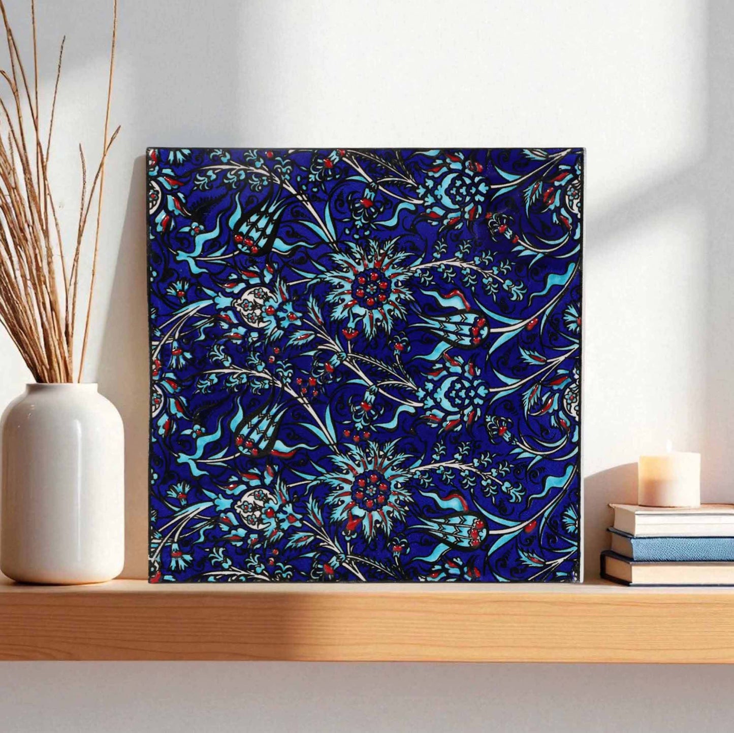 Ceramic tile with a blue floral pattern on a wooden shelf.
