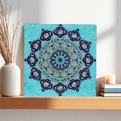 Decorative blue and white mandala ceramic tile on a wooden shelf with a vase and books.