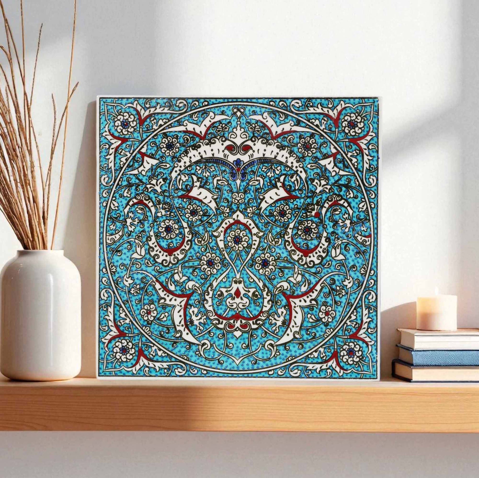 Decorative ceramic tile with intricate blue and white pattern on a shelf with a vase and books.