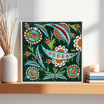 Decorative floral ceramic tile on a wall with a vase and books in the background