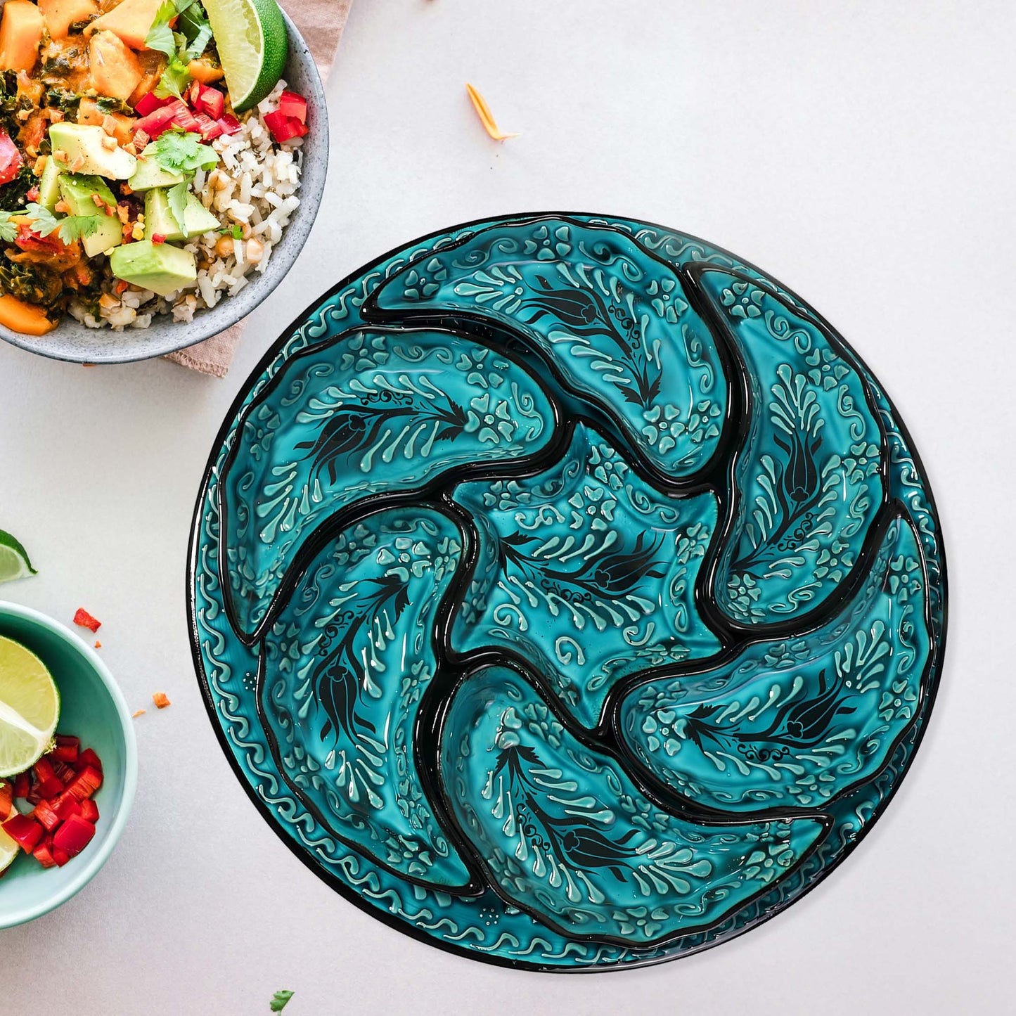 Decorative turquoise snack serving tray set with black patterns on a white surface with bowls of food.