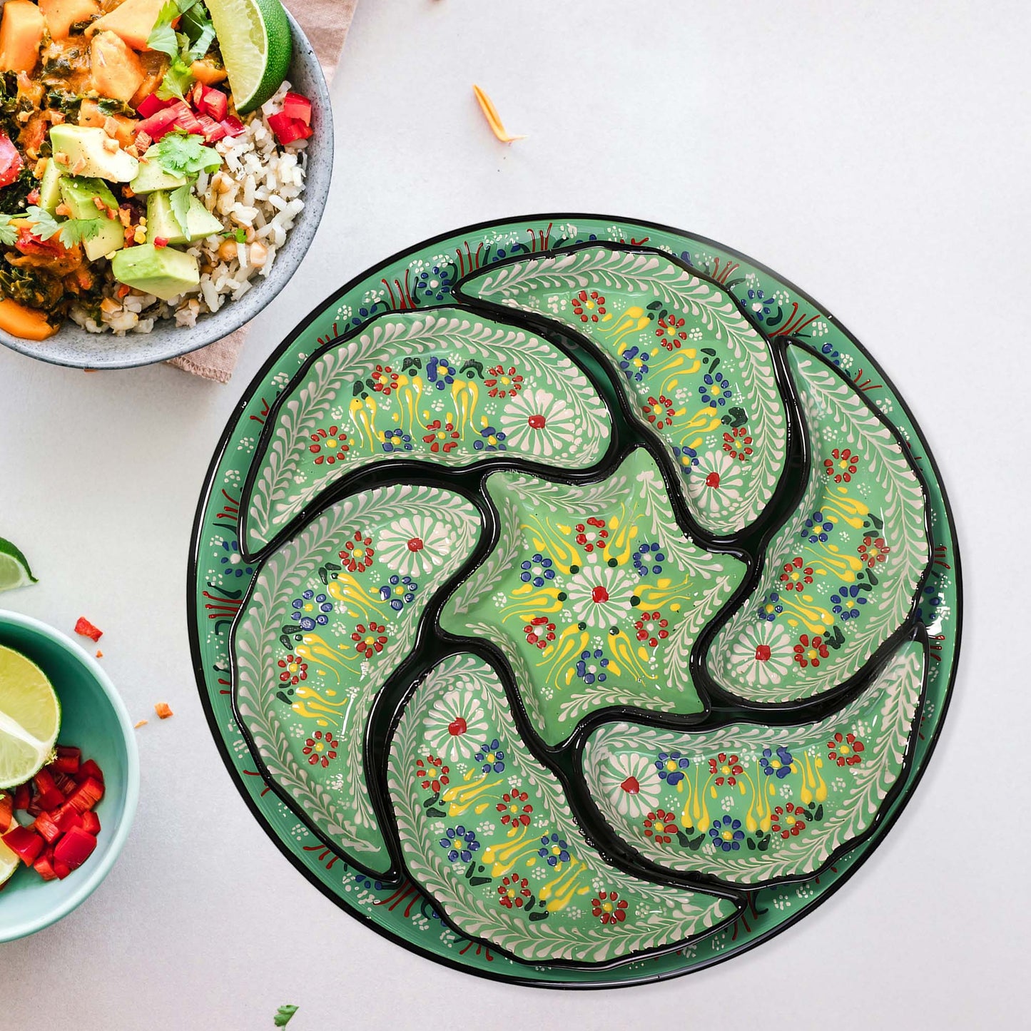 Decorative green snack serving tray set with floral patterns on a white surface with bowls of food.