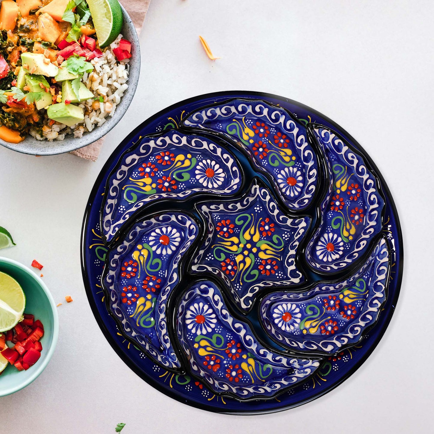 Colorful paisley-patterned snack serving tray set on a white surface with bowls of food.