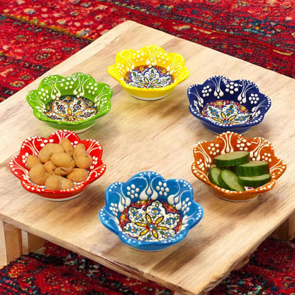 Colorful ceramic dip bowls on a wooden table with a patterned rug background