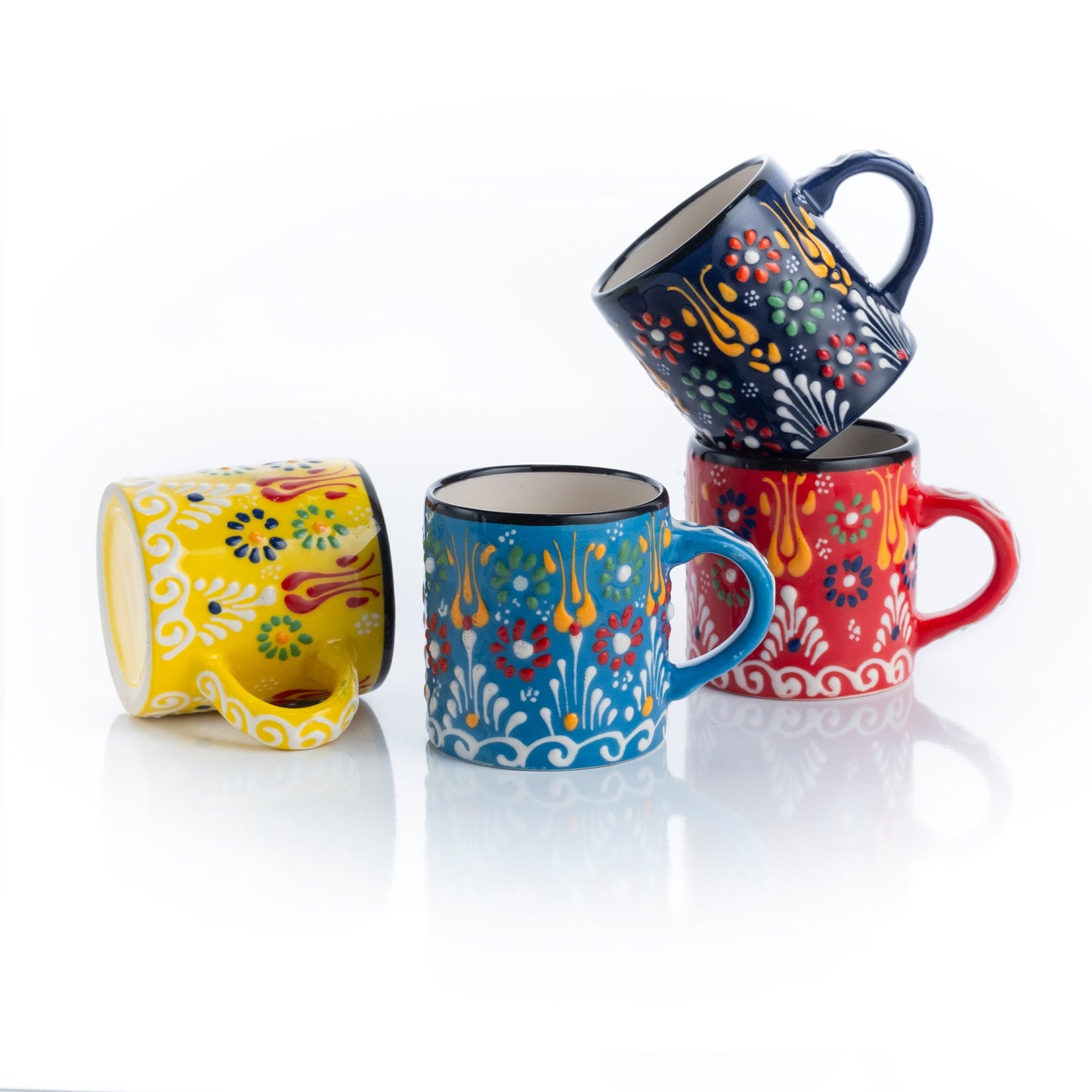 A set of four ceramic espresso cups in red, blue, yellow, and green colors with floral patterns.