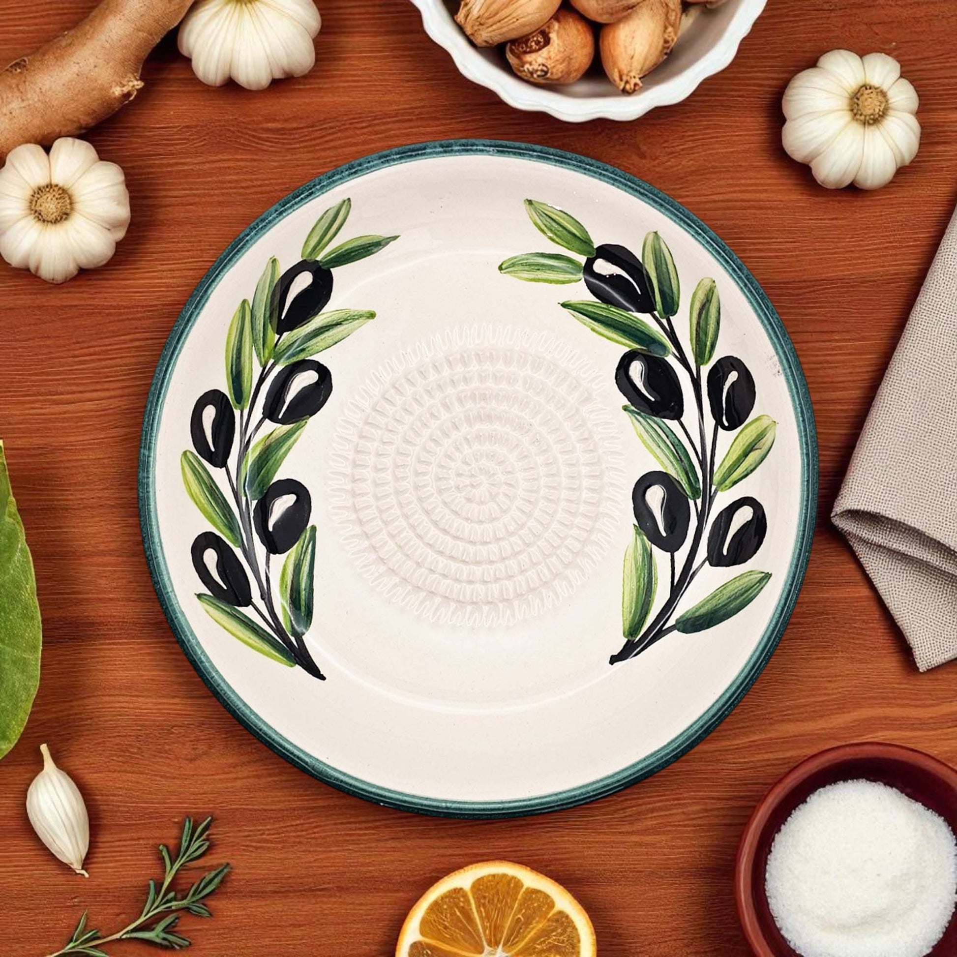 Ceramic garlic grater bowl with olive design on a wooden table with ingredients