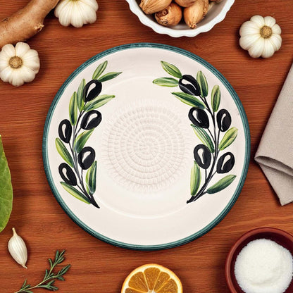 Ceramic garlic grater bowl with olive design on a wooden table with ingredients
