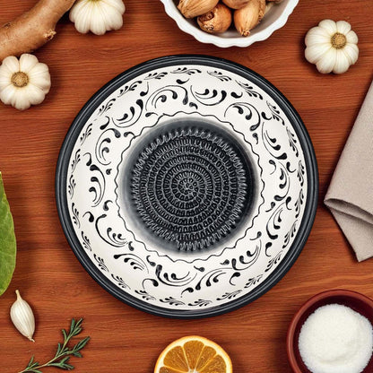 Decorative ceramic garlic grater bowl with black and white patterns on a wooden surface with autumn-themed items.