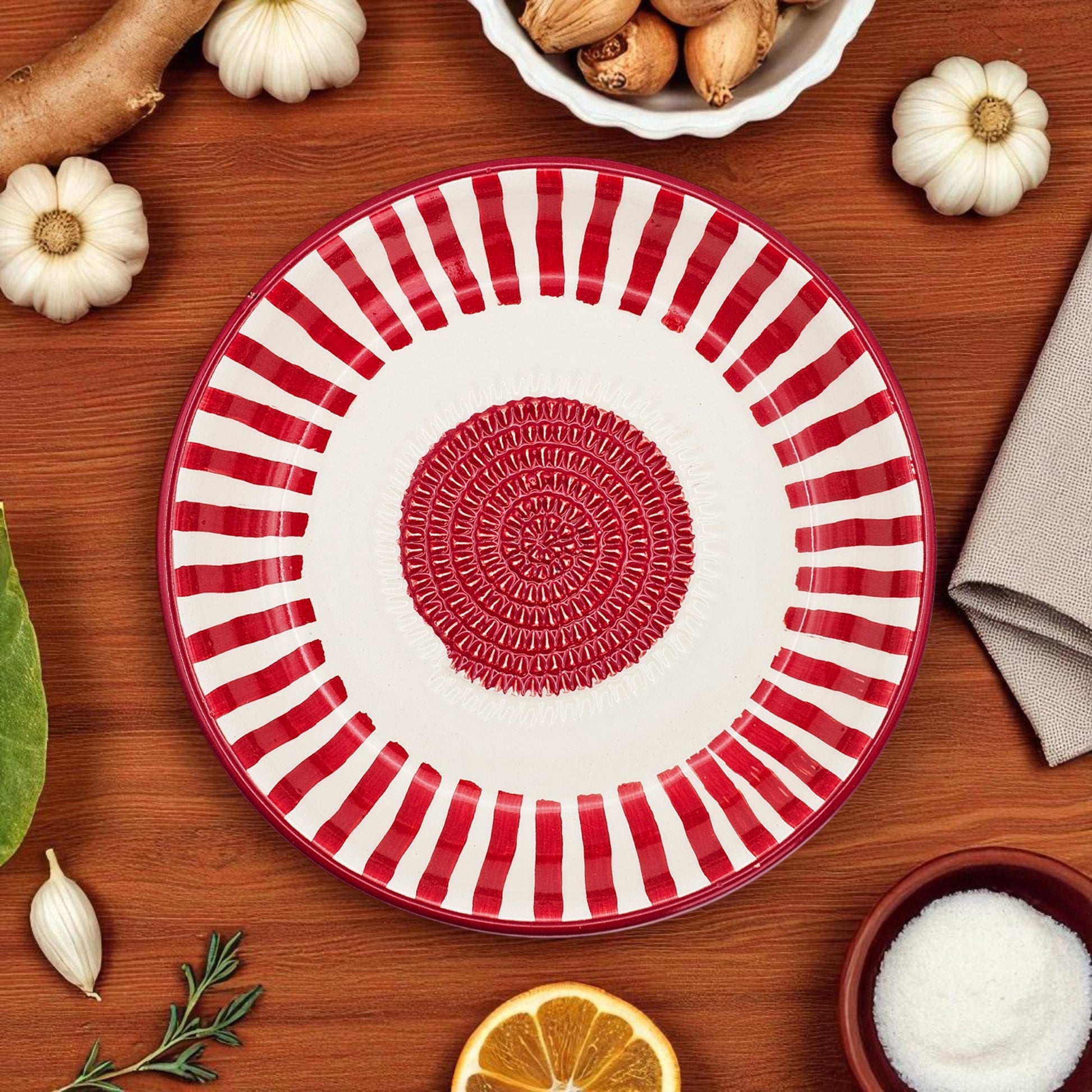 Red and white striped garlic grater bowl with decorative center on a wooden table with autumnal items.