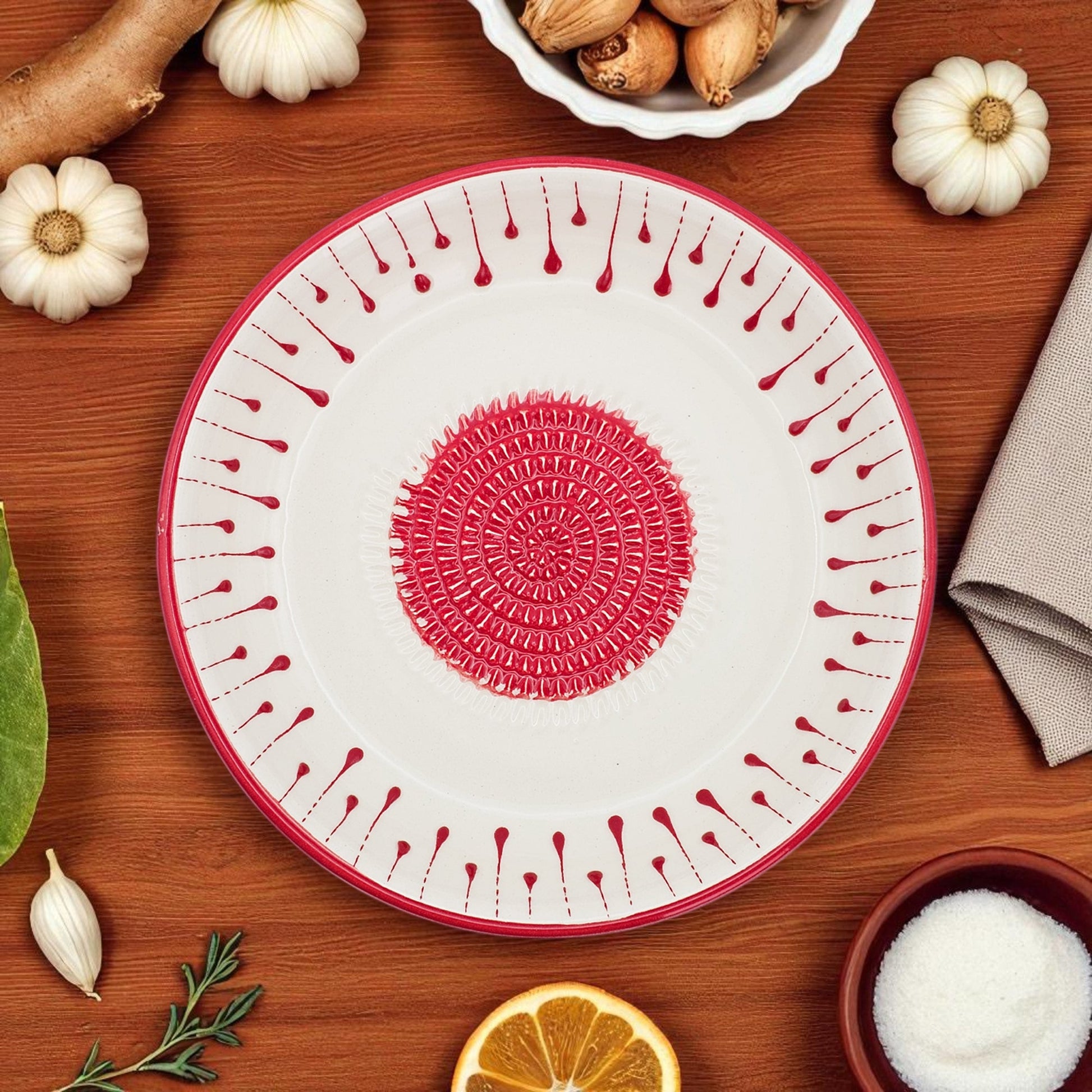 Decorative garlic grater bowl with red patterns on a wooden surface with pumpkins and a napkin.