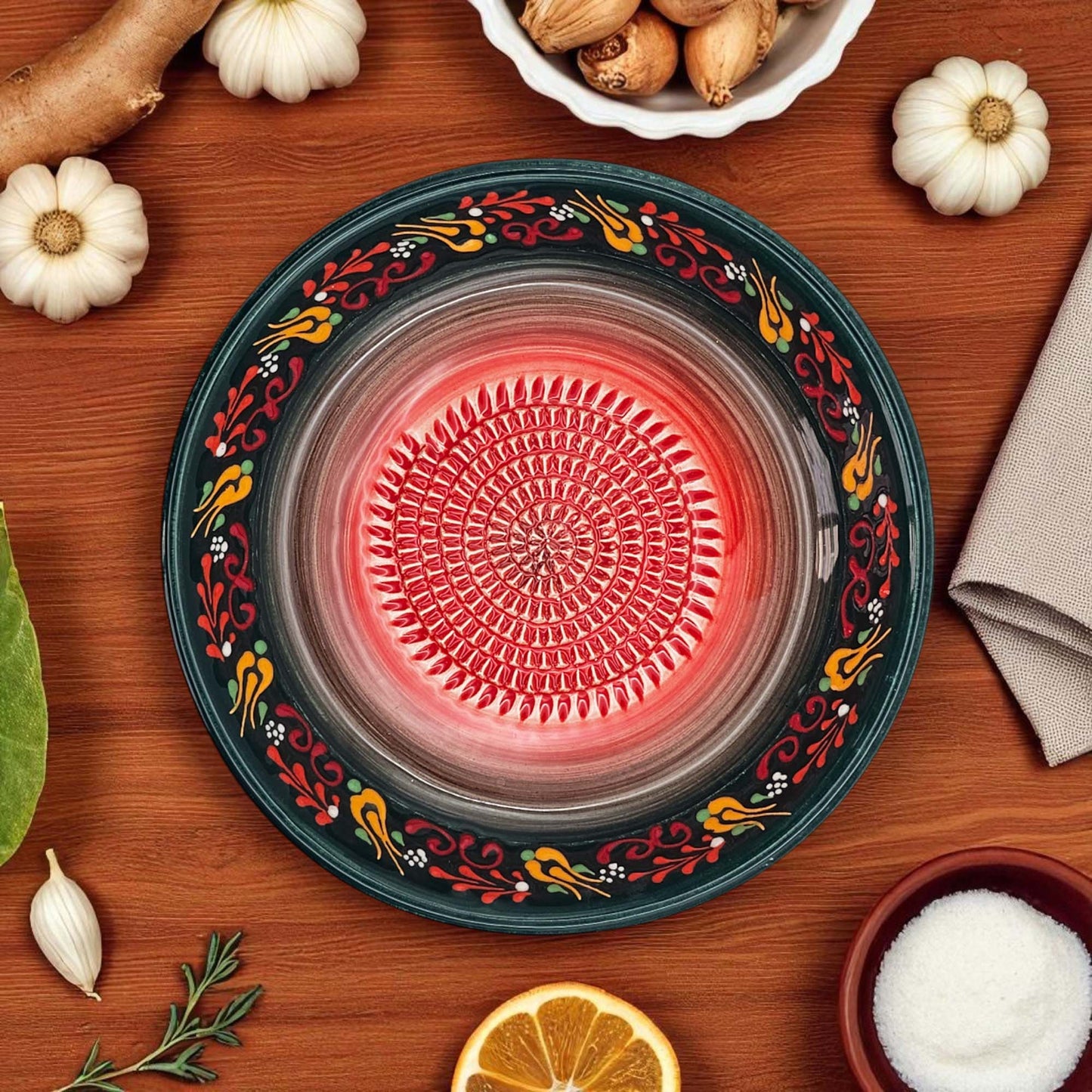 Decorative garlic grater bowl with floral patterns on a wooden surface with ingredients