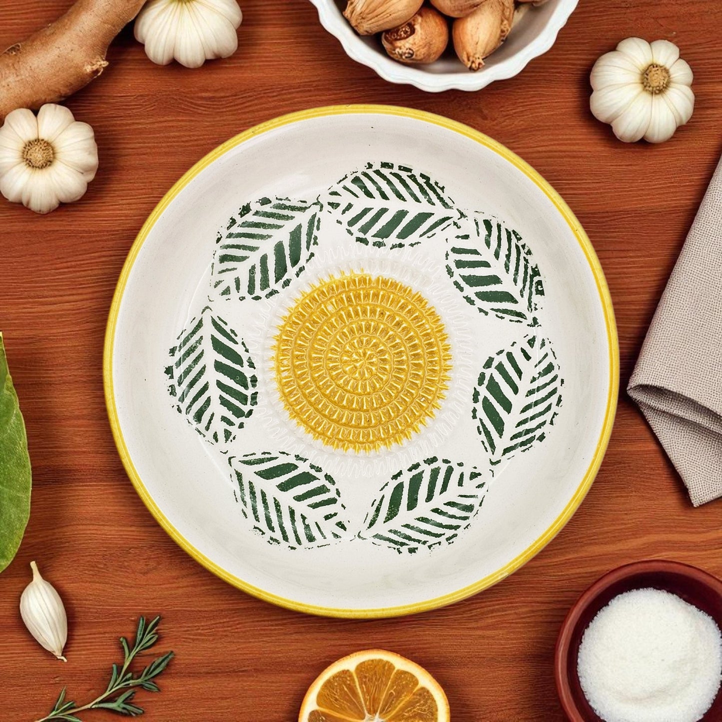Decorative garlic grater bowl with green leaf pattern on a wooden surface
