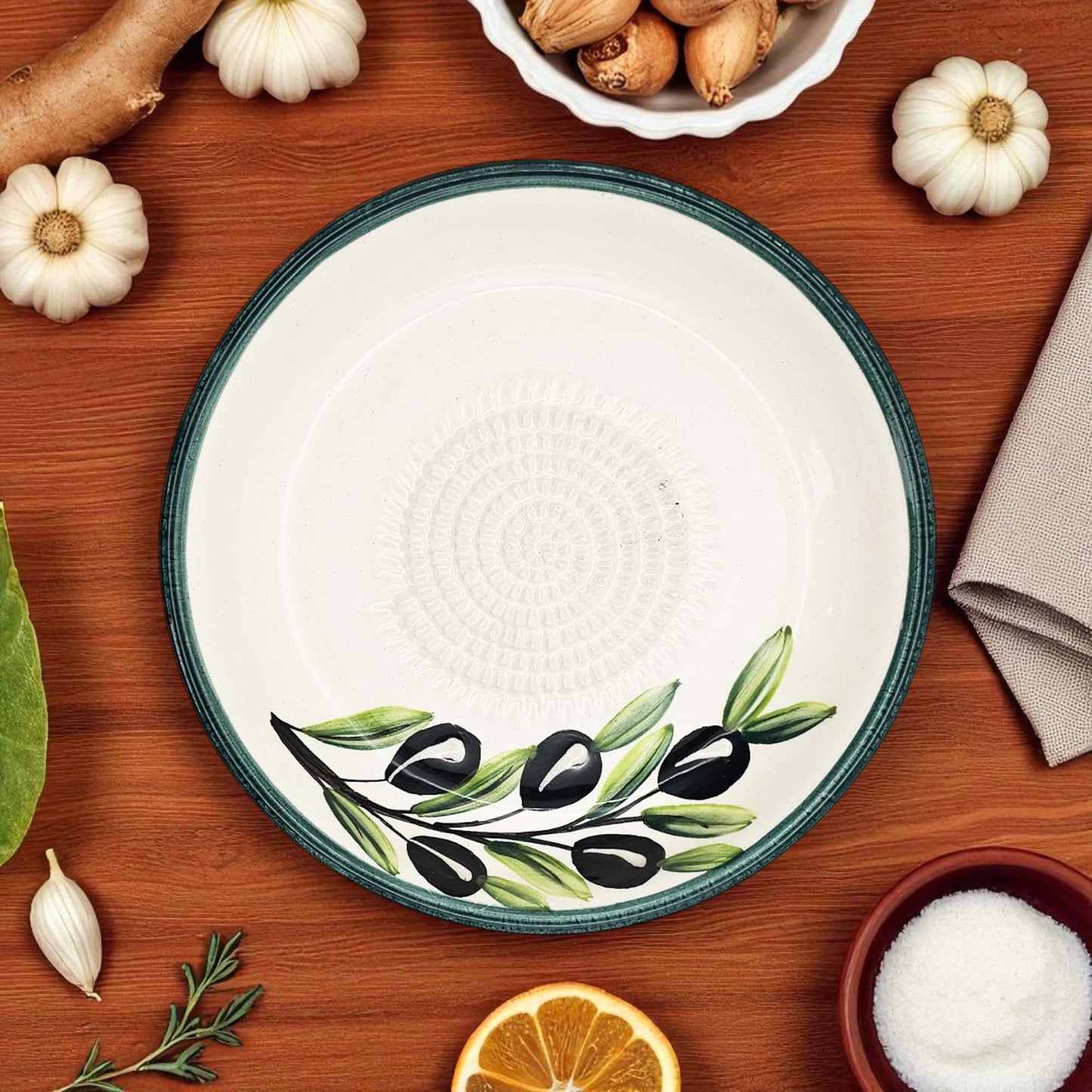 Decorative garlic grater bowl with olive design on a wooden table with ingredients