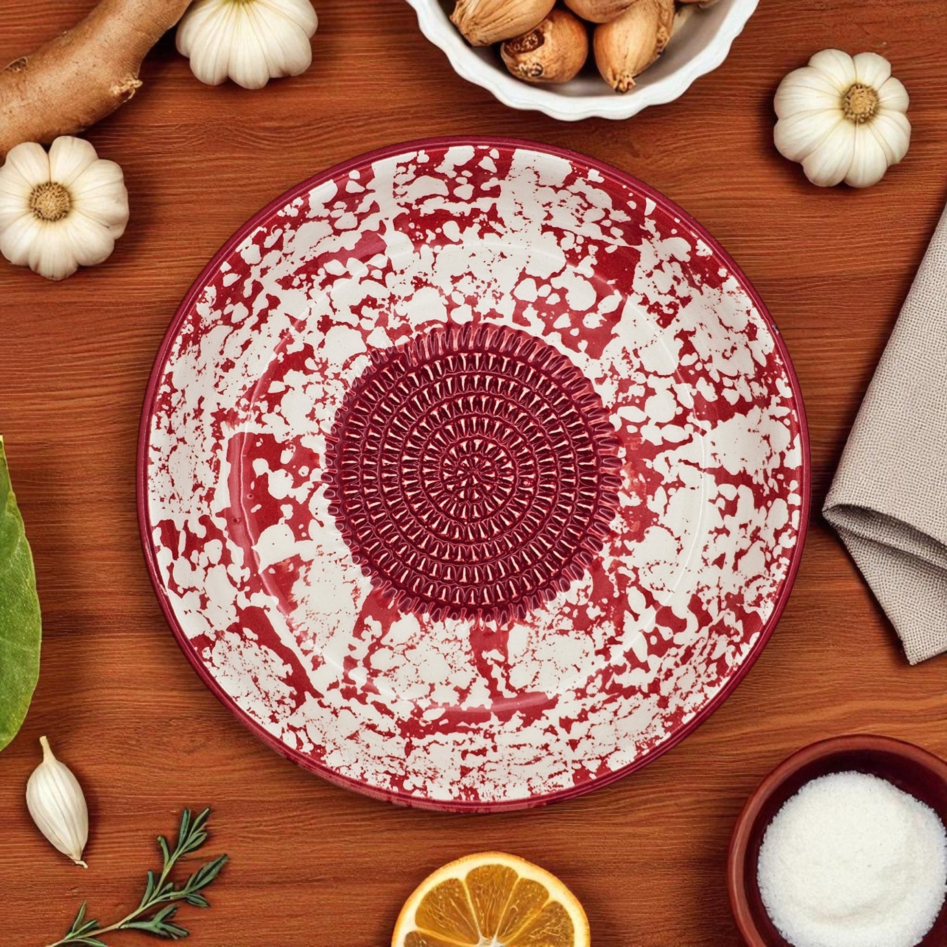 Decorative red and white garlic grater bowl on a wooden surface with pumpkins and other items.