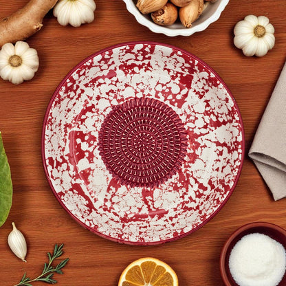 Decorative red and white garlic grater bowl on a wooden surface with pumpkins and other items.