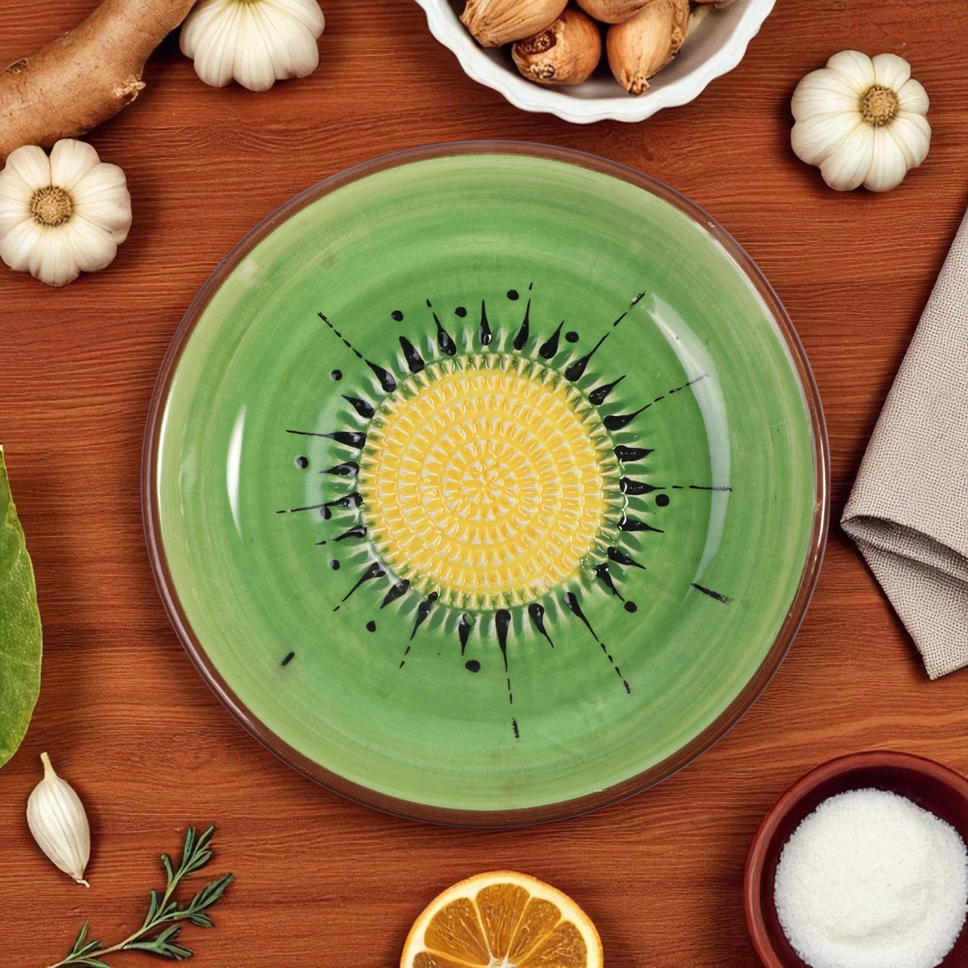 Green ceramic garlic grater bowl with yellow center and black patterns on a wooden table with autumn-themed items.