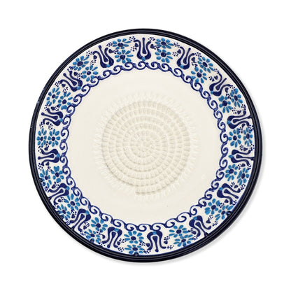 Decorative garlic grater plate with blue floral pattern on a white background