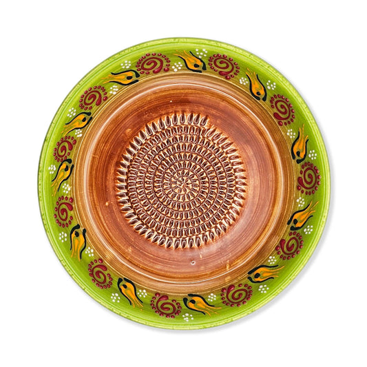 Ceramic garlic grater bowl with decorative green rim and brown center on a white background