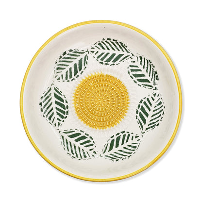 Ceramic garlic grater bowl with yellow center and green leaf patterns on a white background