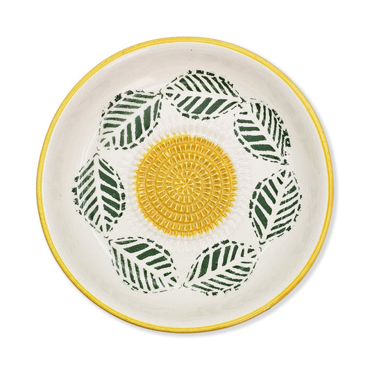 Ceramic garlic grater bowl with yellow center and green leaf patterns on a white background