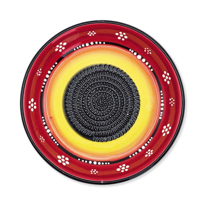 Decorative garlic grater bowl with red, yellow, and black design on a white background