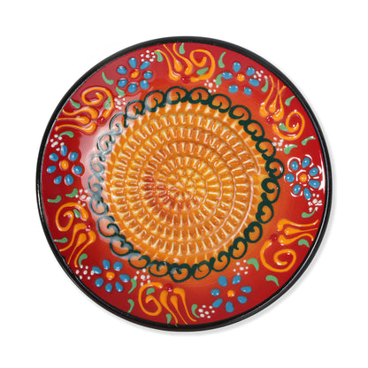 Decorative ceramic garlic grater plate with colorful floral patterns on a red background