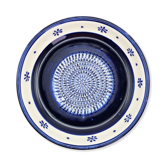 Ceramic garlic grater bowl with blue and white decorative rim on a white background