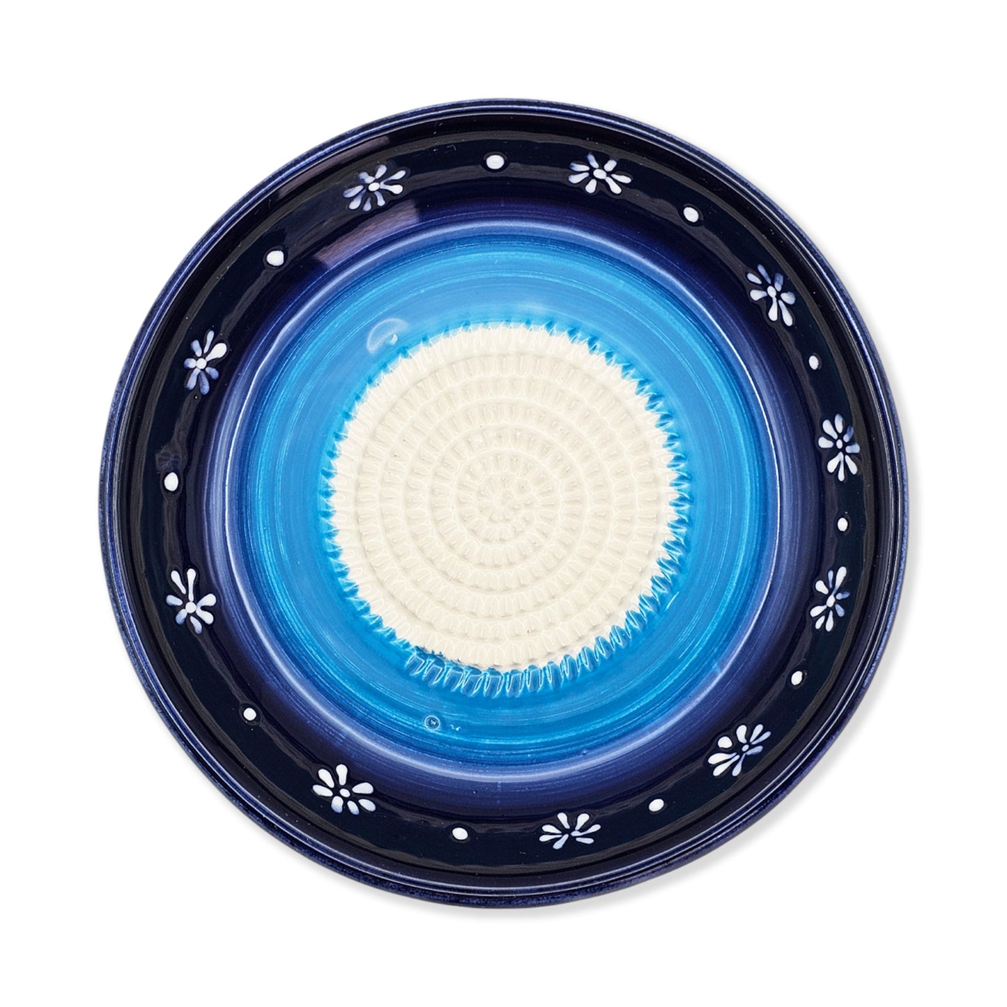 Blue ceramic garlic grater bowl with white floral patterns on a white background