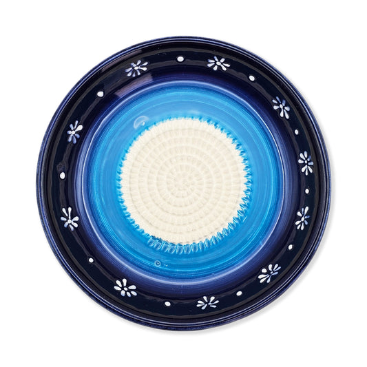Blue ceramic garlic grater bowl with white floral patterns on a white background