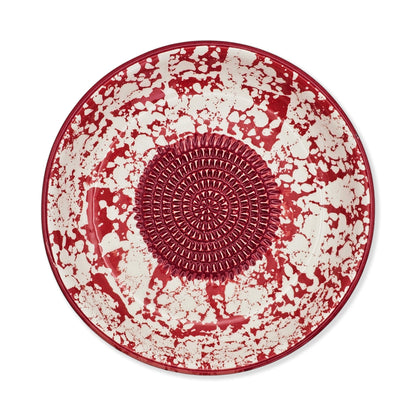 Red and white ceramic garlic grater bowl with textured center on a white background