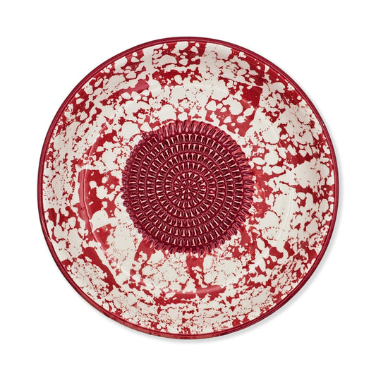 Red and white ceramic garlic grater bowl with textured center on a white background