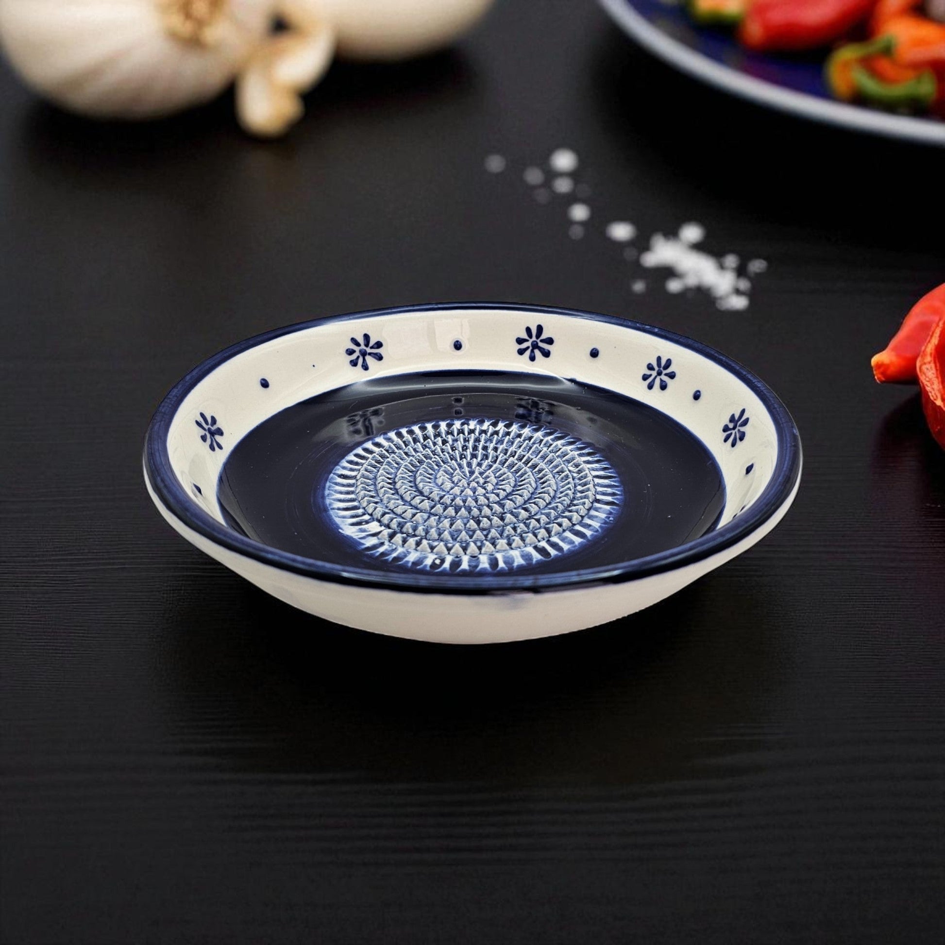 Ceramic garlic grater bowl with decorative blue pattern on a black surface
