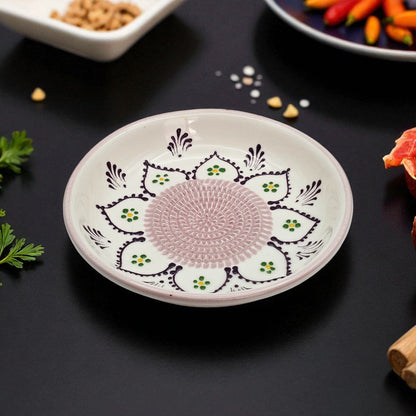 Decorative ceramic garlic grater bowl with intricate patterns on a dark surface with food items.