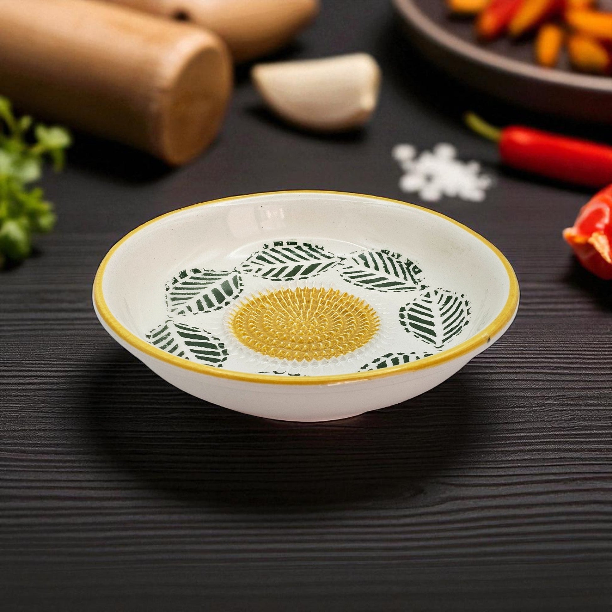 Decorative garlic grater bowl with leaf pattern on a dark surface