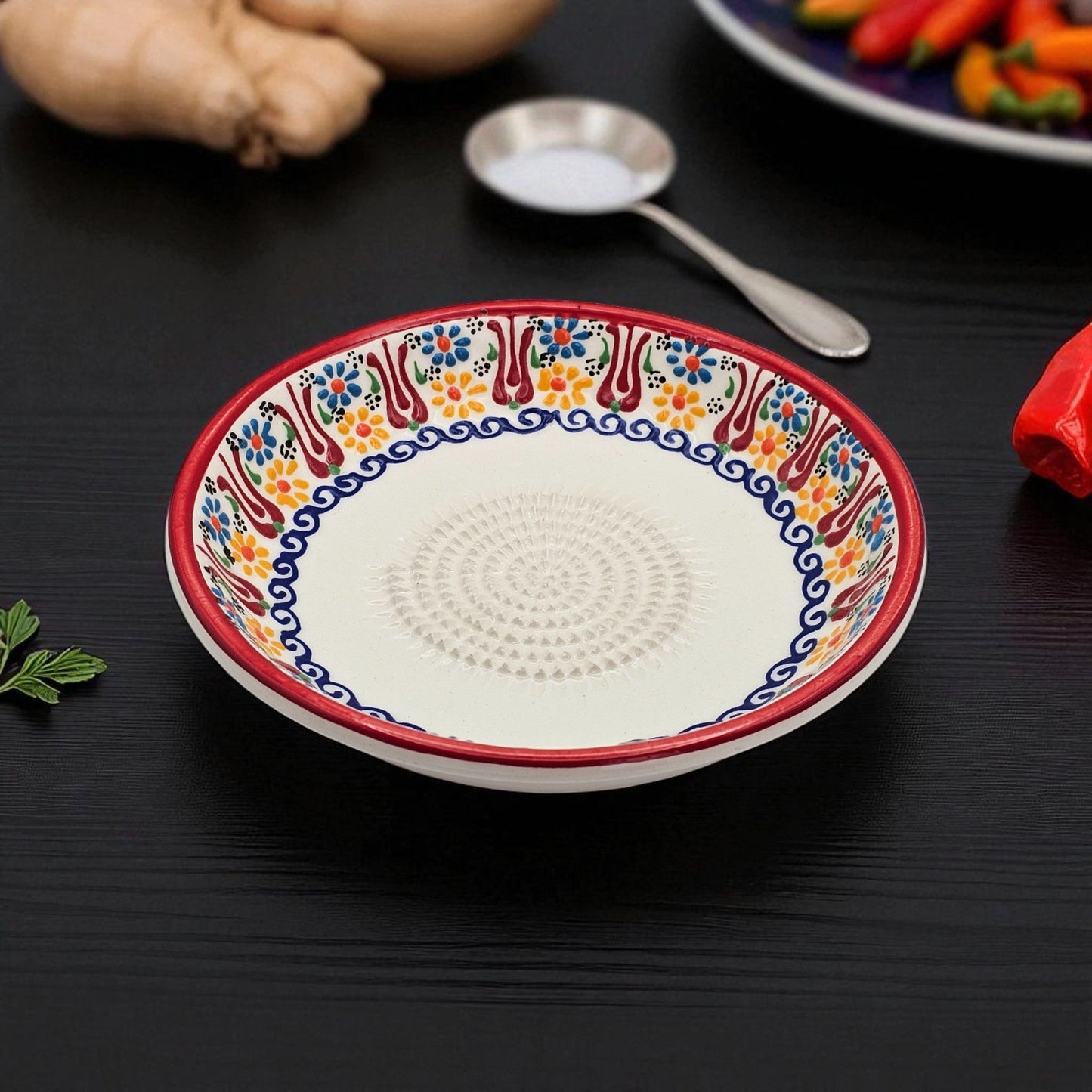 Decorative ceramic garlic grater bowl with colorful patterns on a dark surface