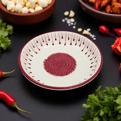 Decorative garlic grater bowl with red patterns on a dark surface with ingredients around