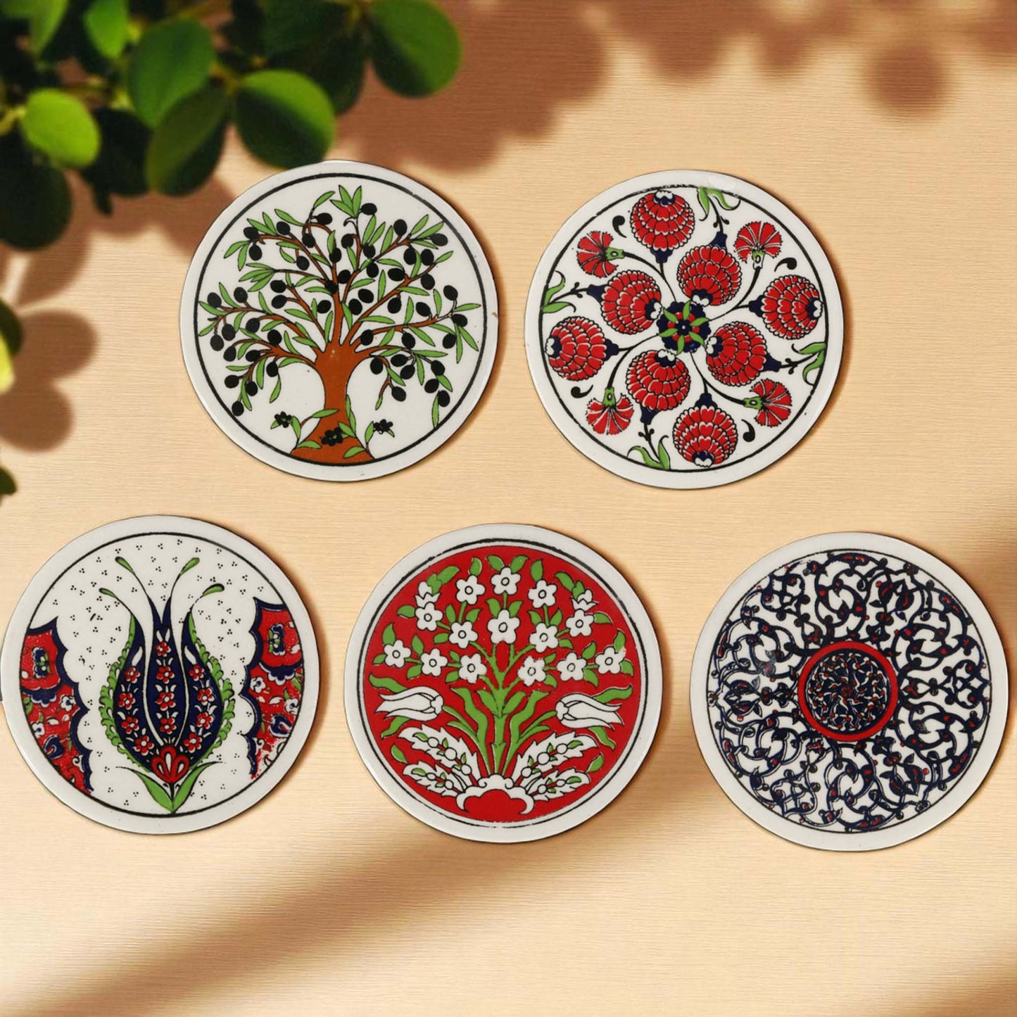 Set of five decorative coasters with various patterns on a beige surface.