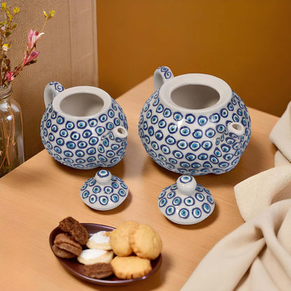 Two ceramic teapots with blue and white patterns on a wooden surface with cookies and a plate.