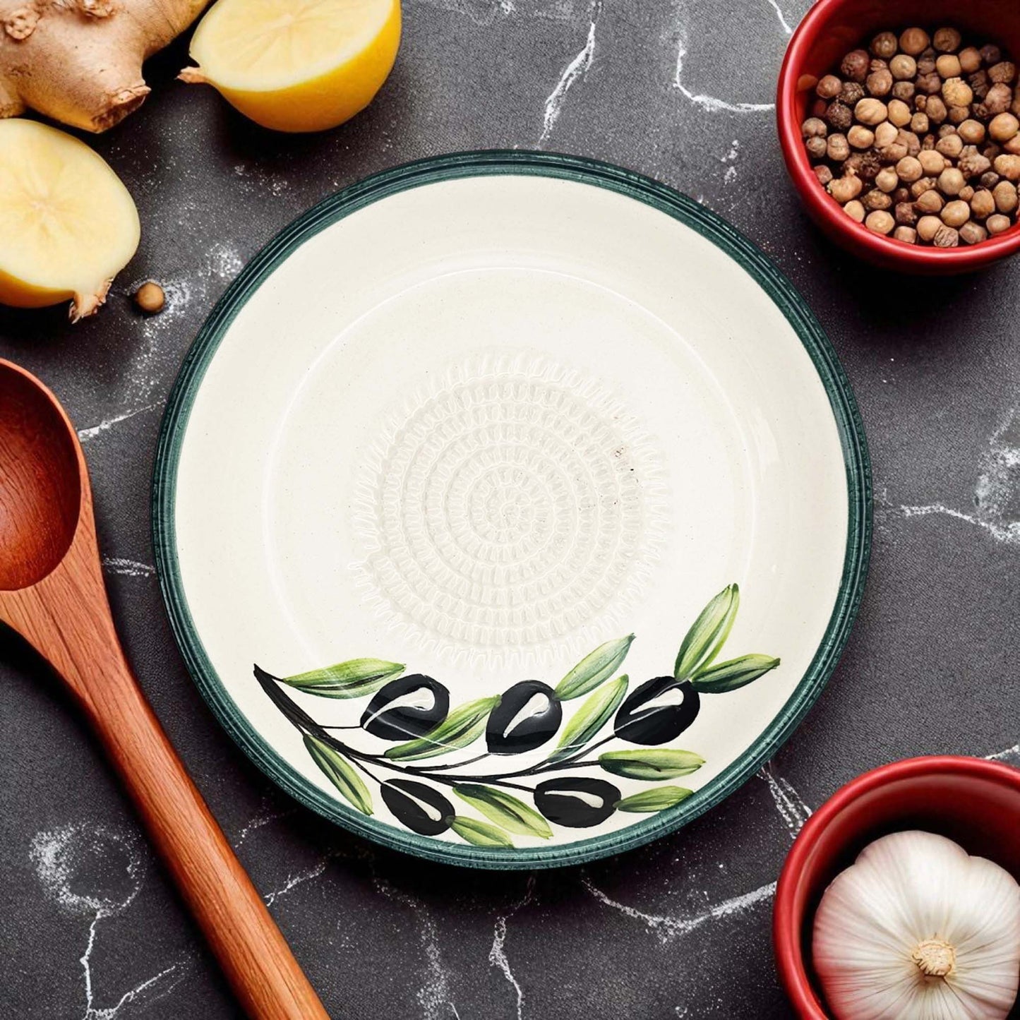 Decorative garlic grater bowl with olive design on a kitchen counter with ingredients