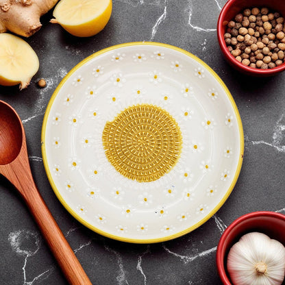 Decorative ceramic garlic grater bowl with geometric design on a dark surface with kitchen items.