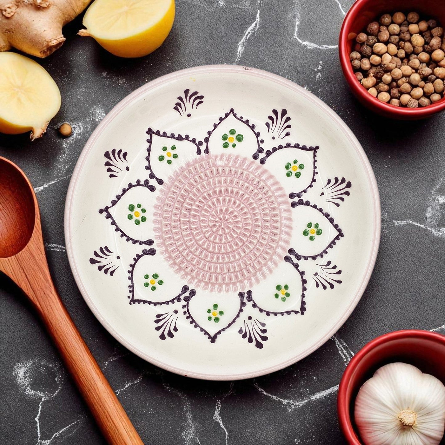 Decorative ceramic garlic grater bowl with intricate patterns on a dark surface with kitchen items.