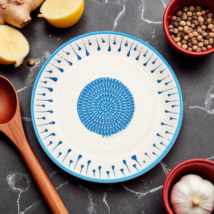 Decorative garlic grater bowl with blue patterns on a dark surface with kitchen items