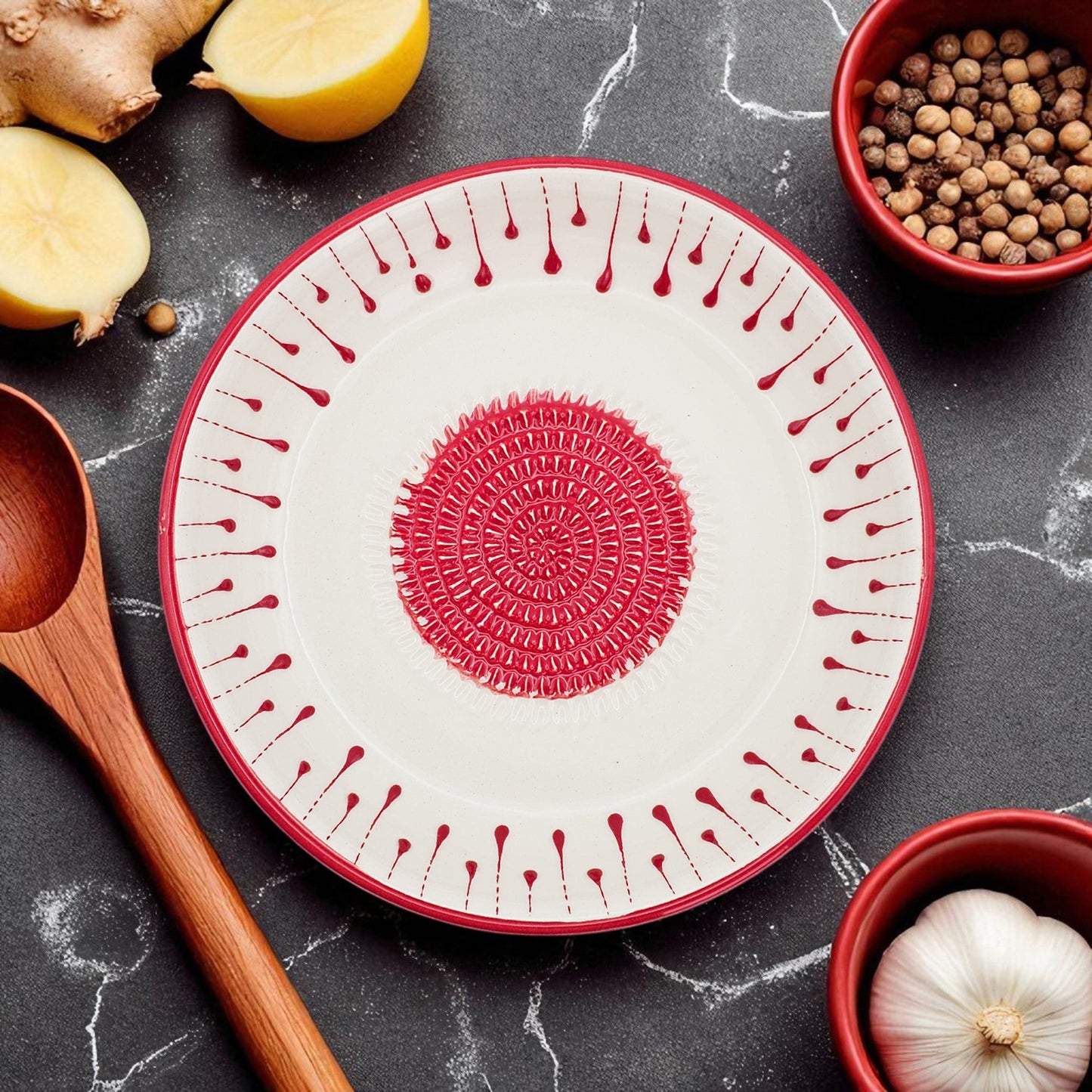Decorative garlic grater bowl with red patterns on a dark surface with kitchen items
